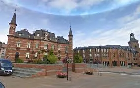 Plombier Frameries inspectant des canalisations dans une rue pittoresque avec maisons en briques et lampadaires anciens