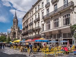 Vue sur une rue animée de Saint Gilles, expert réalisant un débouchage de canalisation devant maisons historiques.